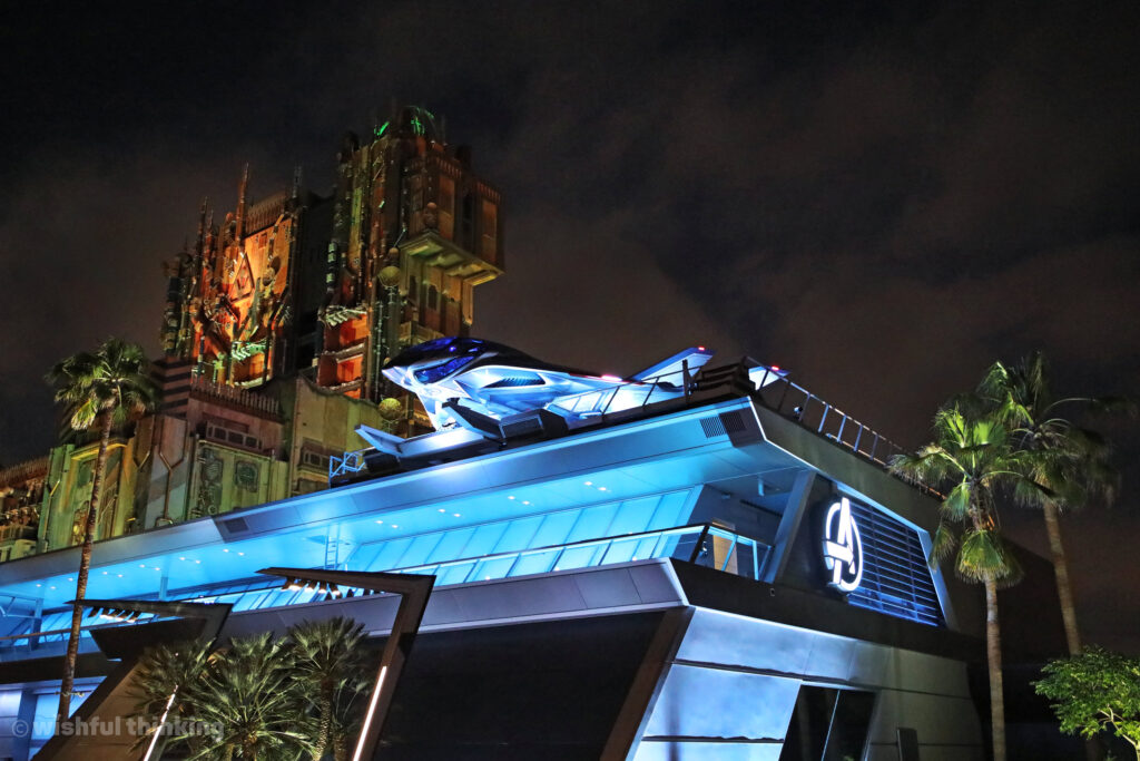 The Quinjet stands on guard above Avengers Campus headquarters with Guardians of the Galaxy Mission Breakout in the distance