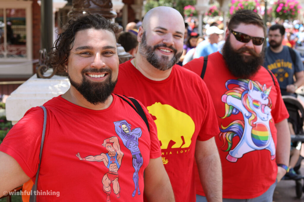 Gay Days Orlando -- three men in red t-shirts show their LGBTQ+ pride at the Magic Kingdom in Walt Disney World