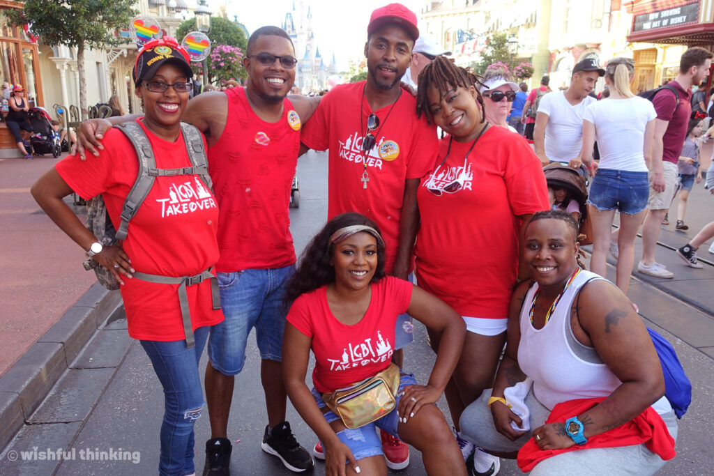 A group of friends in red t-shirts smiles on Main Street USA during Gay Days in Orlando, Florida