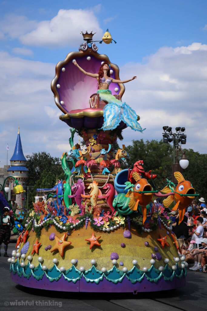 During a bright sunny day, Ariel sits in her shell and waves to guests at Disney's Magic Kingdom park in Orlando, Florida