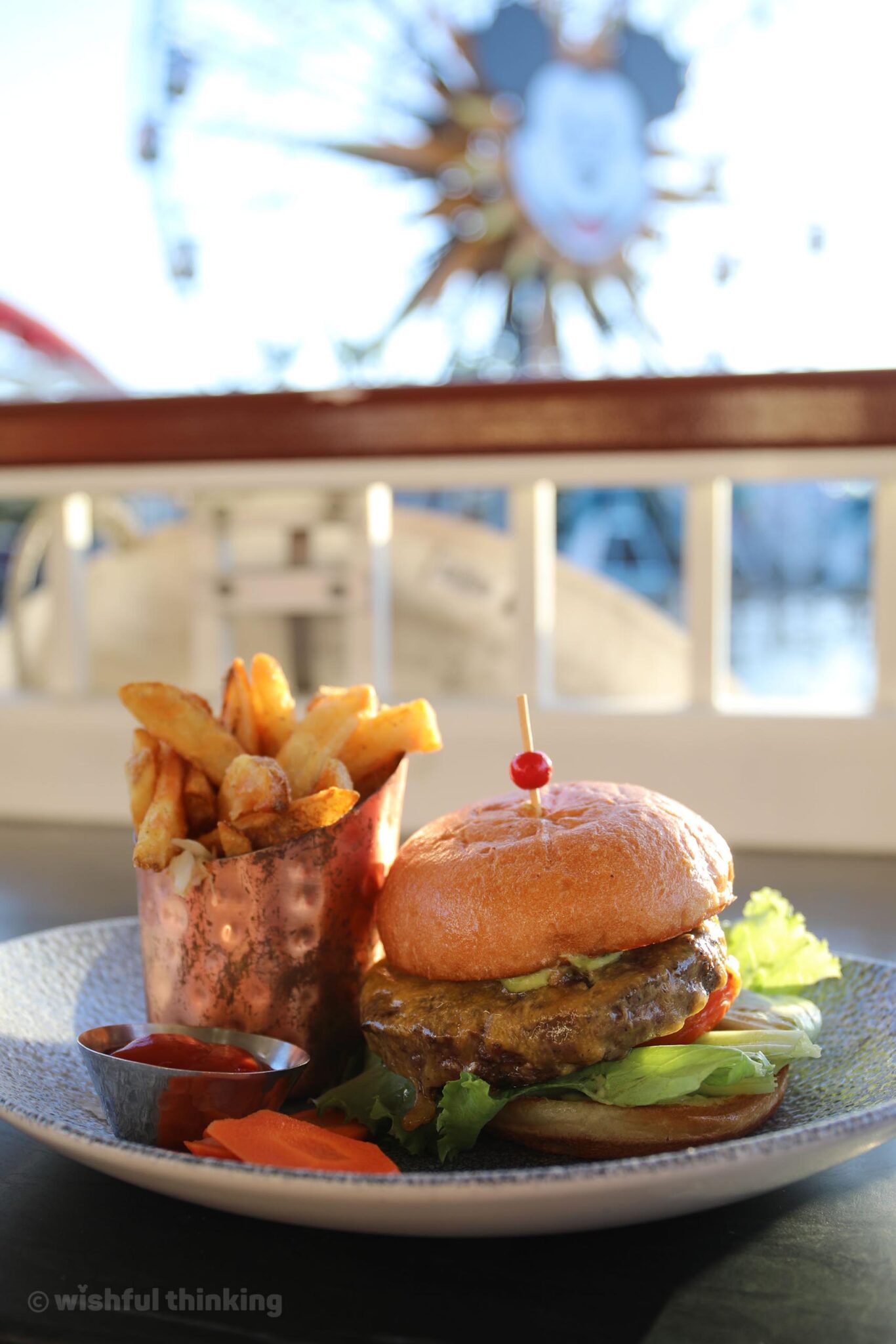 At Lamplight Lounge in Disney California Adventure, a tasty burger and fries tempts diners on a sun-drenched terrace with a view of Pixar Pier
