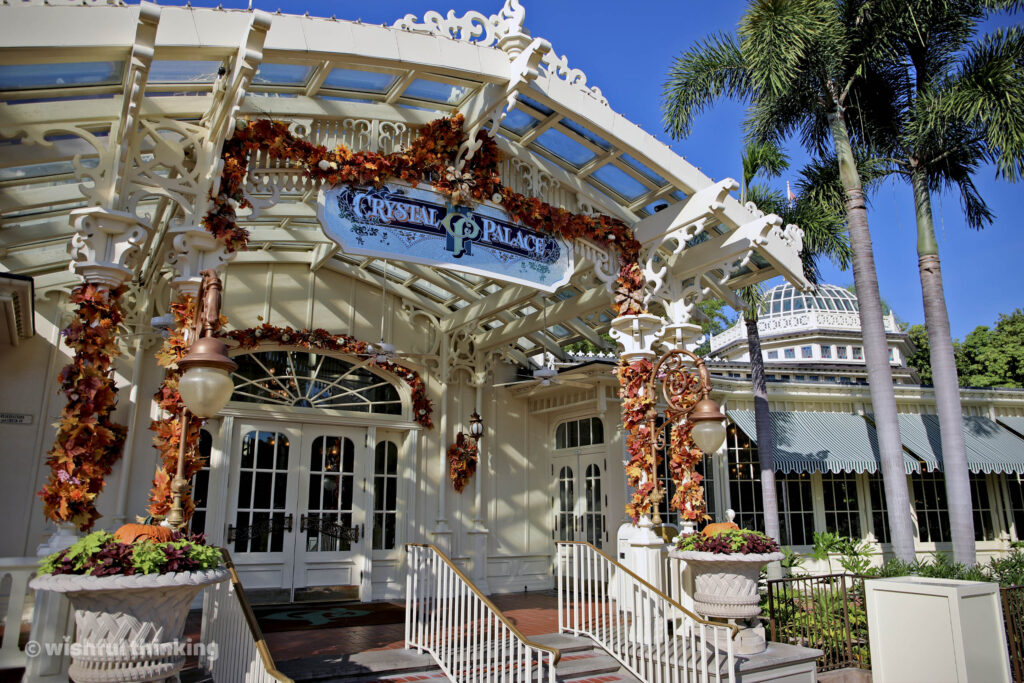 Crystal Palace at Magic Kingdom delights guests on a sunny day with festival fall foliage