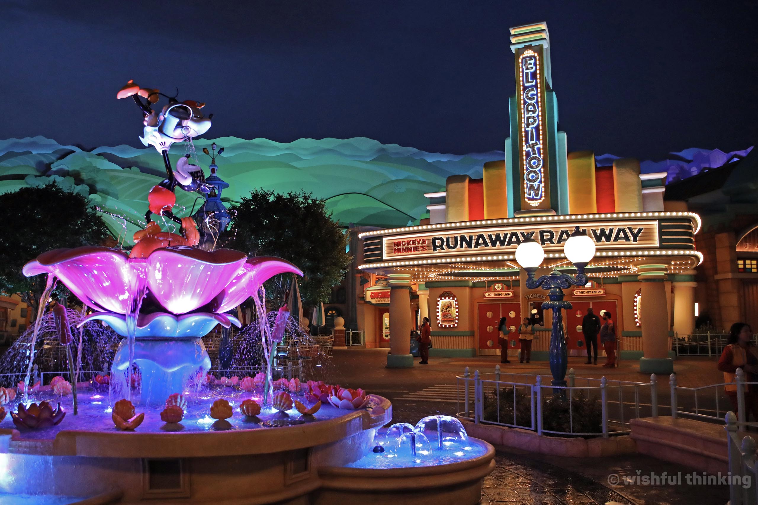 Mickey & Minnie's Runaway Railway at Disneyland's Toontown glows with an inviting marquee and a whimsical Mickey & Minnie fountain